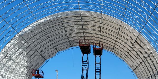 Two elevated work platforms under a large arched construction structure.
