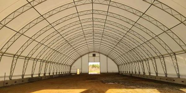 Inside view of a large, empty temporary storage tent with a metal frame.