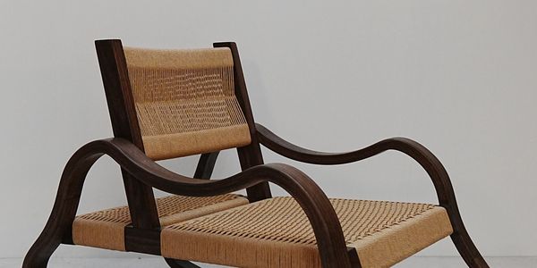 Elegant wooden chair with woven seat and backrest against a plain wall.