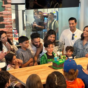 A group celebrates a child's Minecraft-themed birthday party with cake and smiles.