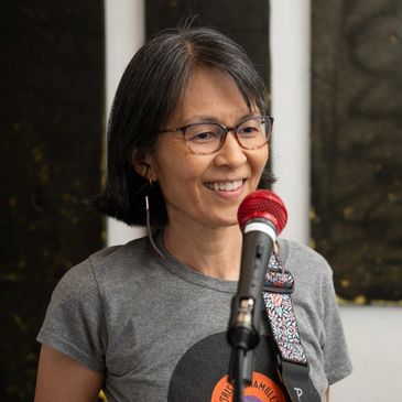 Woman smiling while speaking into a microphone.