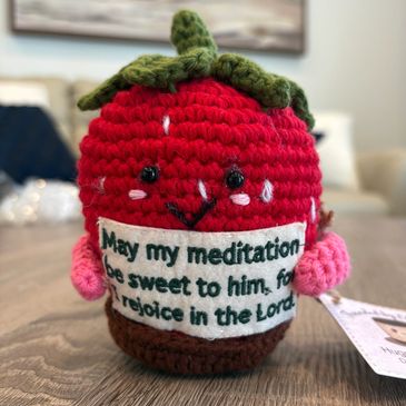 Close-up of a crocheted tomato with a message patch.