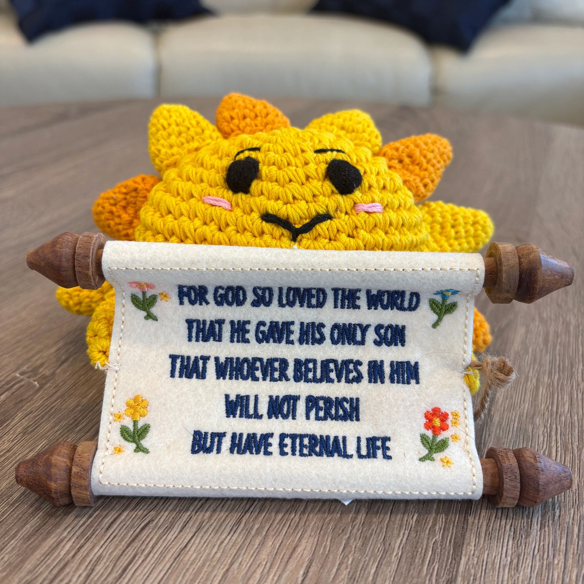 Crocheted sun holding a fabric scroll with a Bible verse.