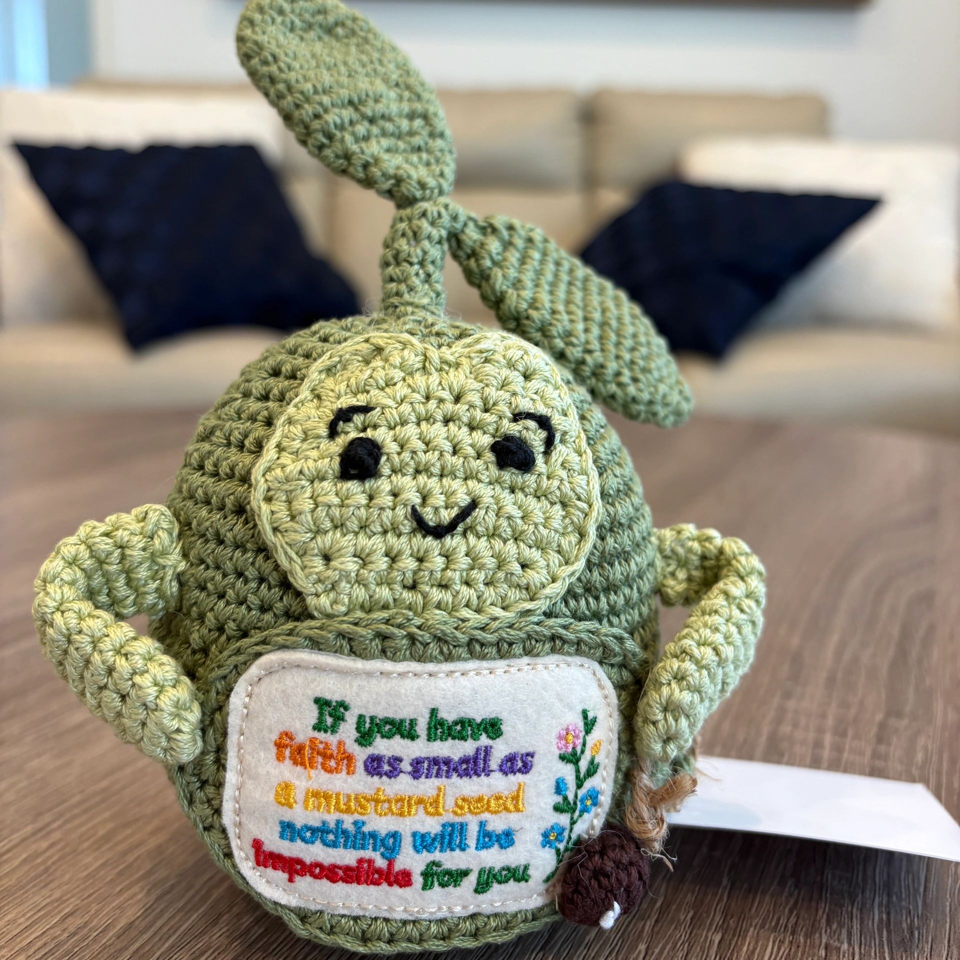 Crocheted green toy with an embroidered inspirational quote.