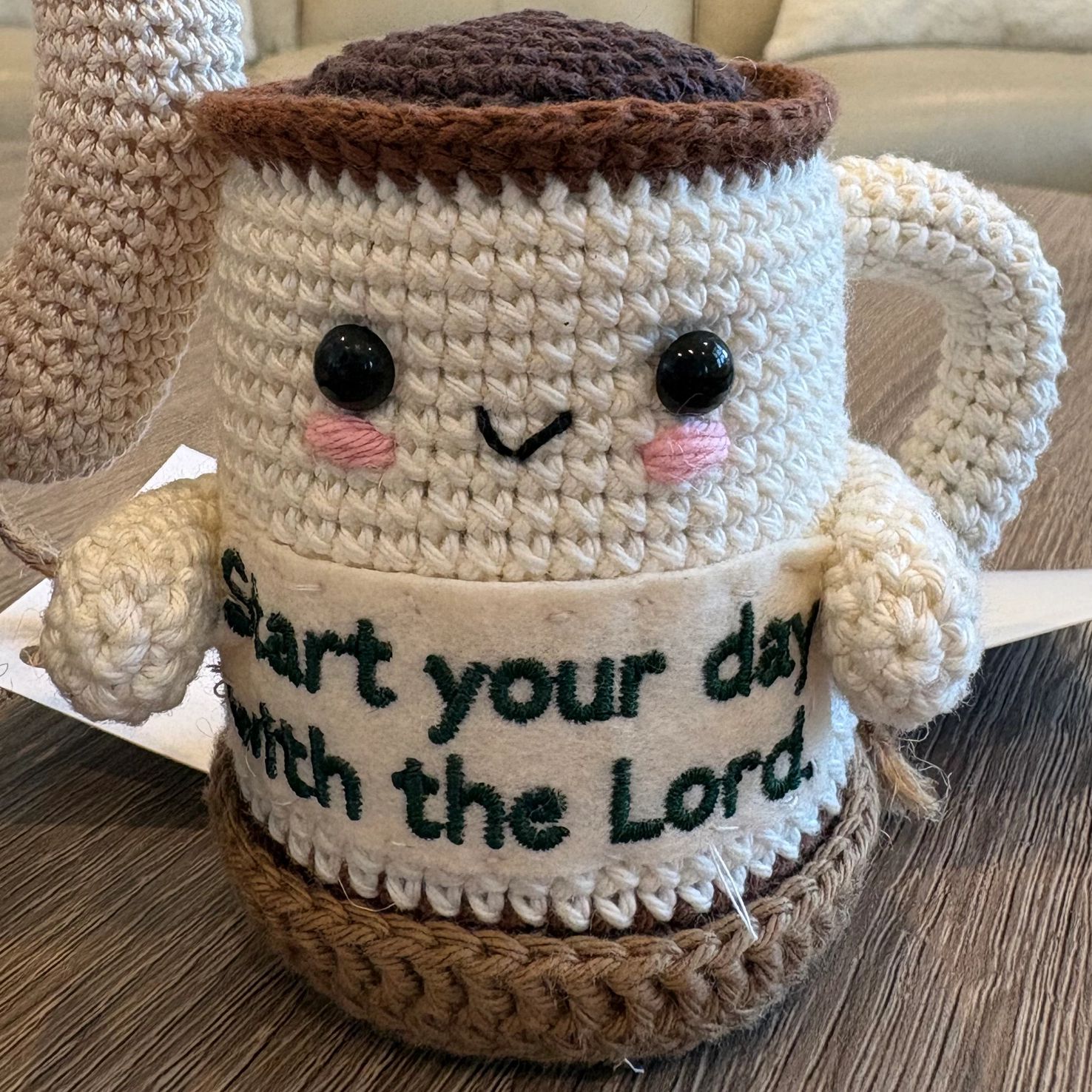Crocheted coffee cup with a happy face and positive message.