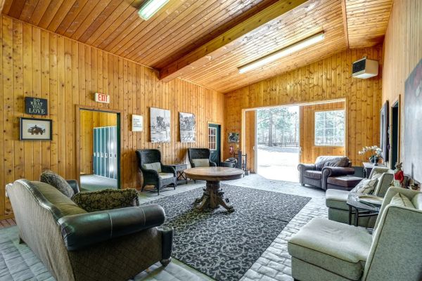 Cozy wooden lounge with sofas and a round table, illuminated by natural light.