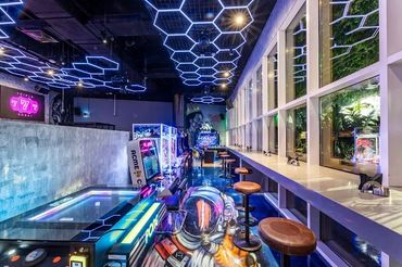 Futuristic arcade with neon hexagonal ceiling lights and colorful gaming machines.
