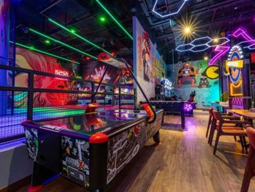 Vibrant arcade room with neon lights and game machines.
