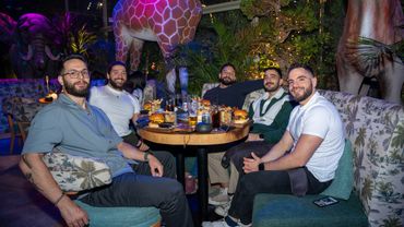 Five men enjoying a meal together in a jungle-themed restaurant with animal statues.