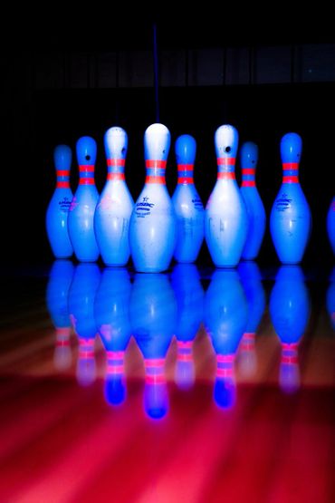 Glowing bowling pins with vibrant blue and red reflections on the lane.