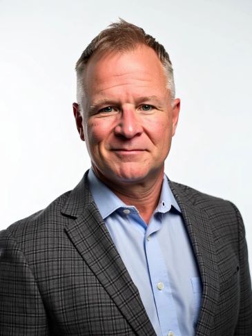 Middle-aged man in a checkered blazer and blue shirt.
