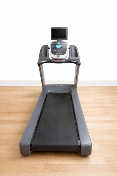 Modern treadmill with digital display and TV screen in a gym.