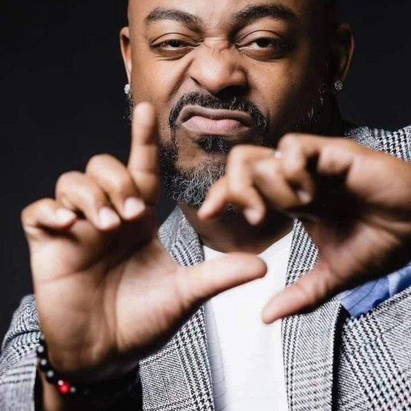 Man making a heart shape with his hands and a playful facial expression.