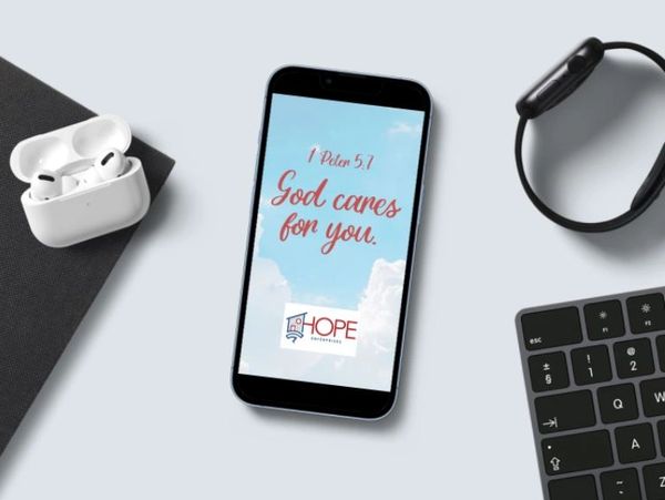 Phone screen displaying a comforting Bible verse with tech accessories nearby.