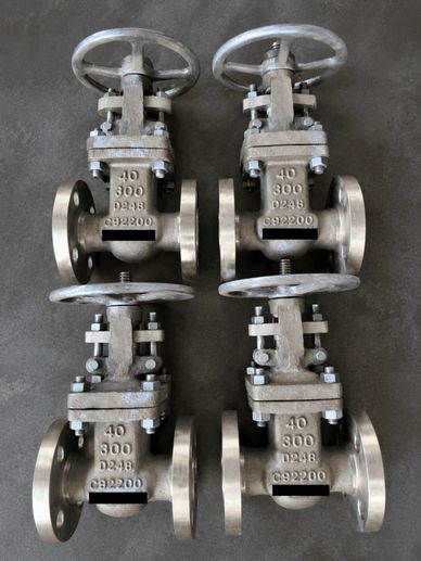 Four industrial metal valves arranged on the floor.