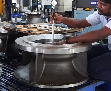 Worker measuring large metal component with precision tool.
