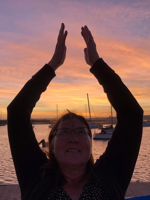 A woman joining hands and praying with river behind