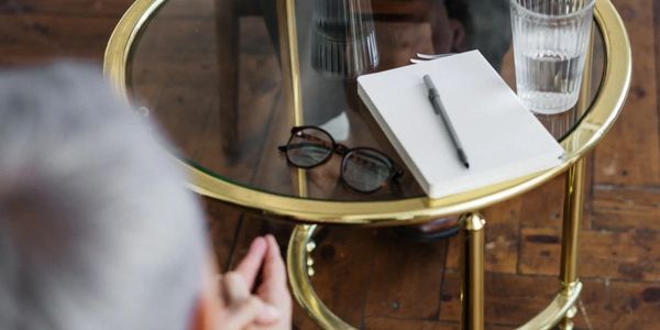 A coffee table with water and a pad of paper in it. burred woman's head in the foreground. 