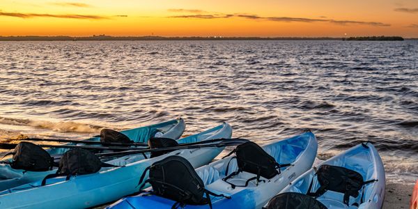 Kayaks on the shoreline with a sunset glow