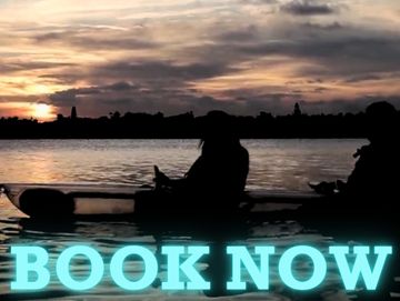 Two people in a clear kayak at sunset with the words "book now" on it in blue. 
