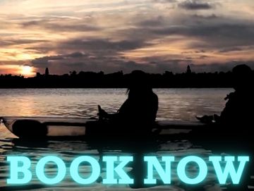 Two people in a clear kayak at sunset with the words "book now" on it in blue. 