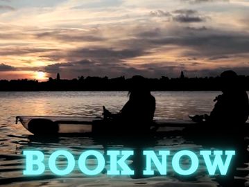 Two people in a clear kayak at sunset