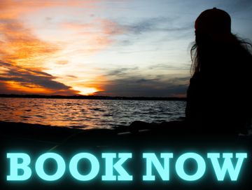 Person on a kayak watching sunset with the words "book now" on it in blue. 