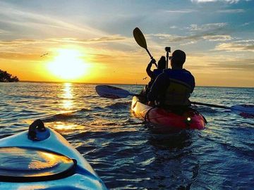 Kayakers paddling into the sunset