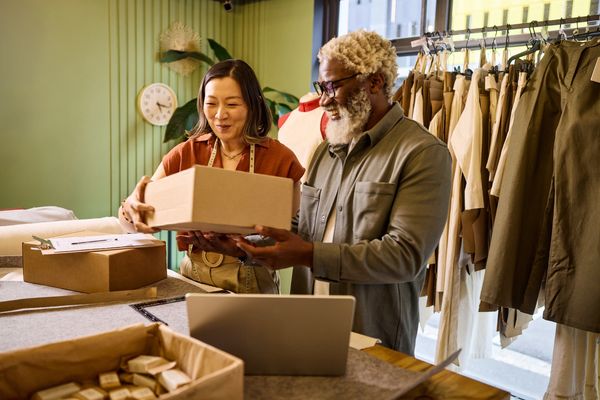 Two smiling small business owners holding a package.