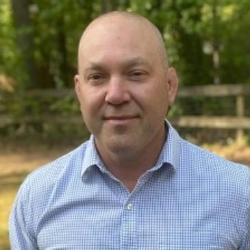 Man in a blue checkered shirt outdoors.
