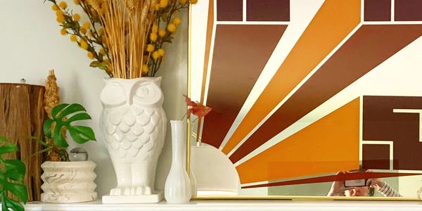 Decorative white owl vase with dried flowers and modern art.