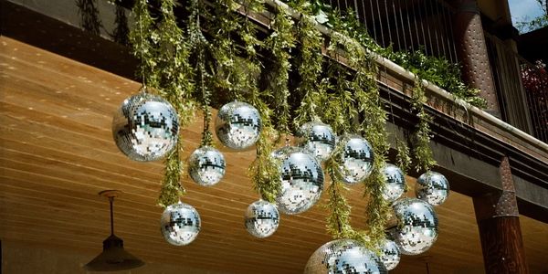 Hanging disco balls and greenery under a wooden ceiling.
