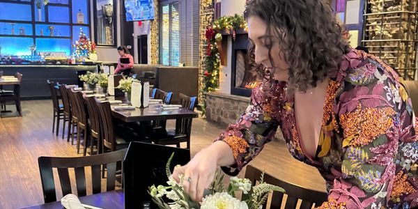 Woman arranging flowers in a cozy restaurant.