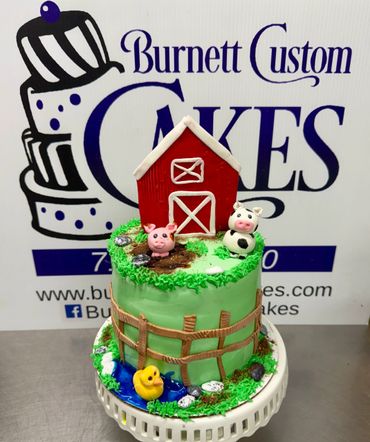 Farm-themed cake with barn, animals, and fence decorations.