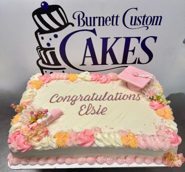 Decorated congratulatory cake with pastel flowers and pink accents.