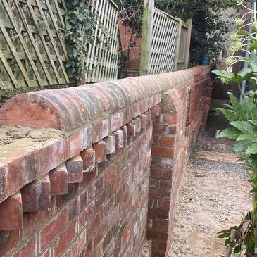 Newly built decorative red brick wall with lattice fence above.