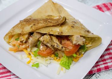Savory chicken wrap with fresh vegetables and cheese drizzled with mustard sauce.