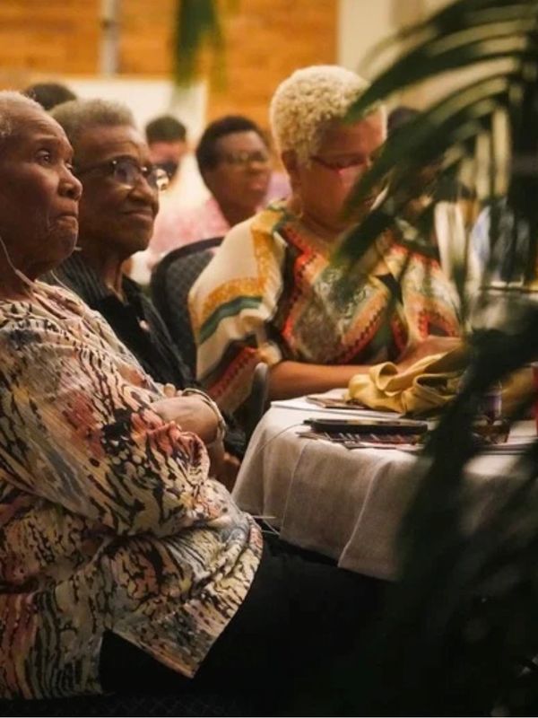 Three elderly women seated at a table during an event.