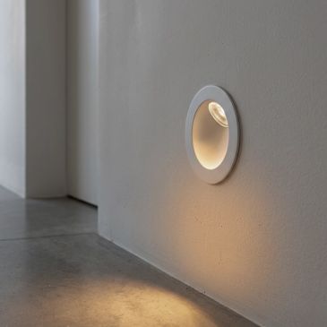 Modern recessed wall light illuminating a concrete floor.