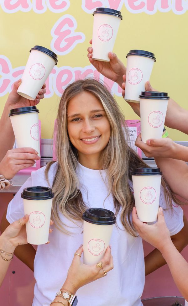 A smiling woman surrounded by hands holding coffee cups from Crispy's Cafe.