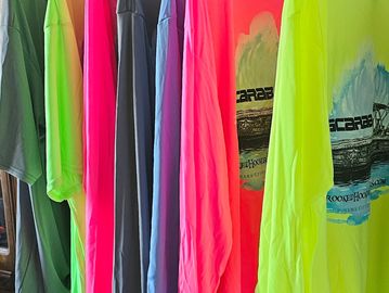 Colorful shirts hanging on a rack in bright neon and pastel shades.