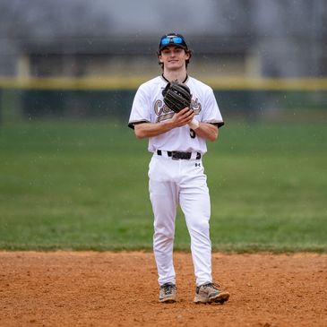 Young baseball player standing on the field with glove.