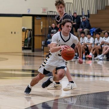 High school basketball player dribbling past defender during a game.