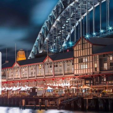 Night view of a lit-up bridge and quay buildings.