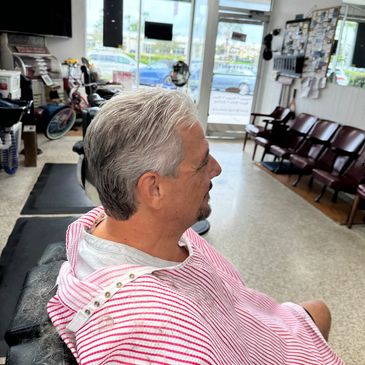 Man with freshly cut gray hair sitting in a barbershop chair.