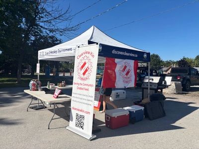 Outdoor community event tent with banners and coolers under clear blue sky.