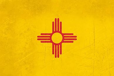 The New Mexico state flag with a red Zia symbol on a yellow background.