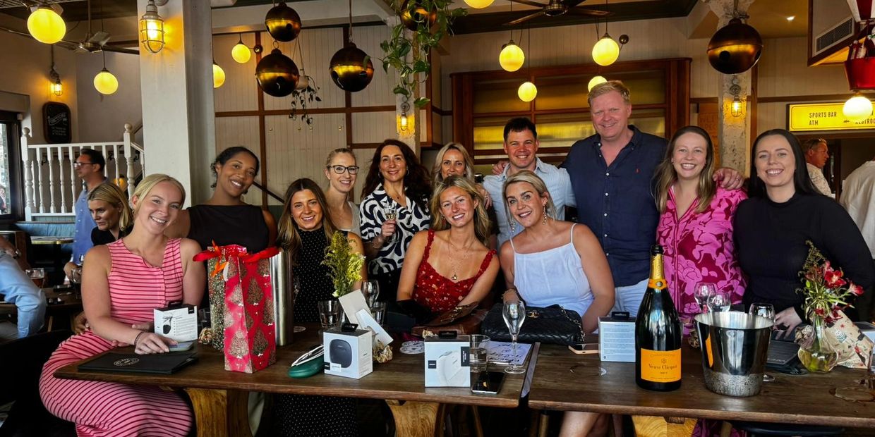 Group of friends smiling and celebrating at a cozy bar with gifts and champagne.