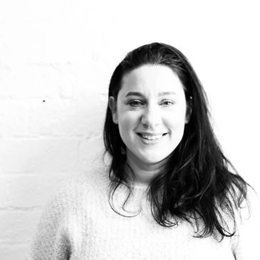 Smiling woman with long dark hair in a light sweater.