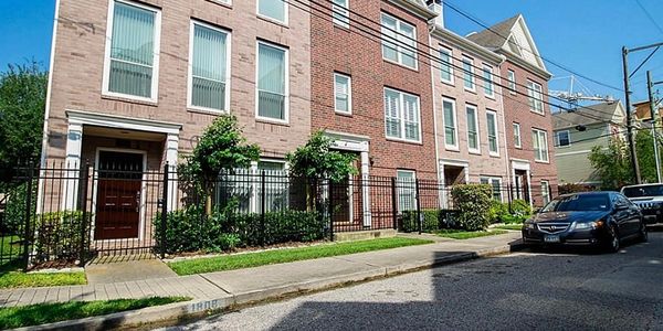 Row of modern townhouses with brick and stone facades under a clear blue sky.